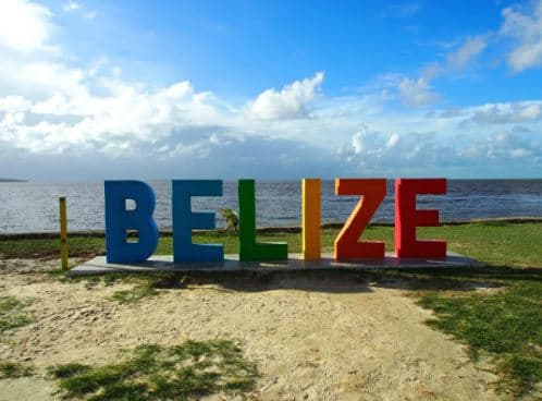 Colorful "BELIZE" sign against a coastal background.
