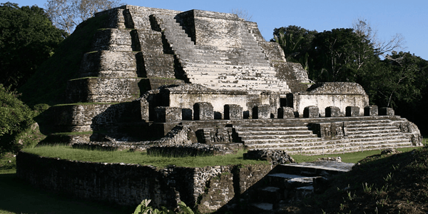 An ancient stone pyramid surrounded by lush greenery.