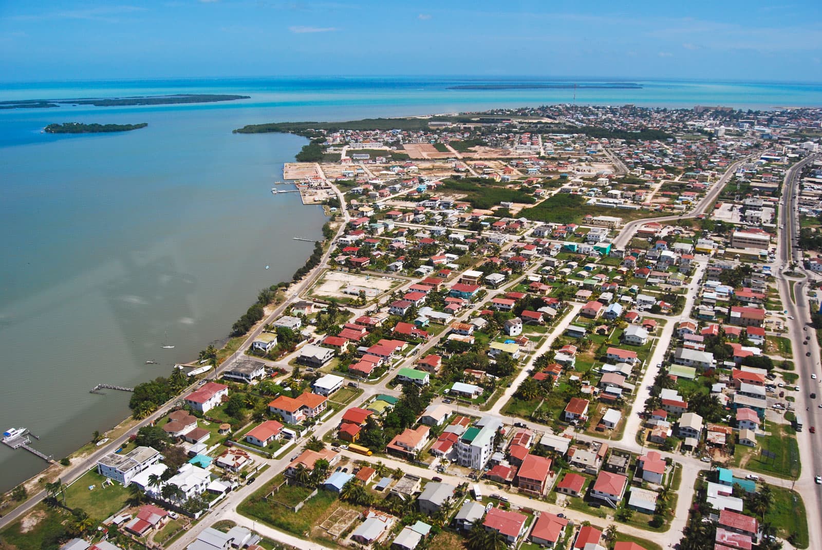 Aerial view of a coastal town bordered by water, with neighborhoods and lush greenery.