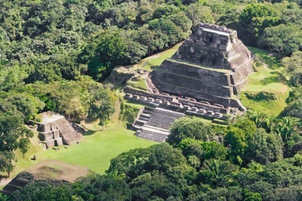Aerial view of a large ancient pyramid surrounded by lush green foliage.
