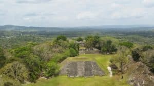 Aerial view of ancient ruins surrounded by lush vegetation and distant hills.