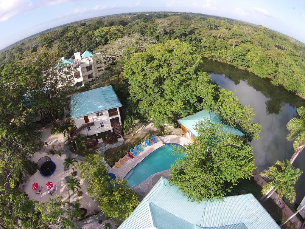 Aerial view of a resort featuring a pool, lush greenery, and a nearby river.