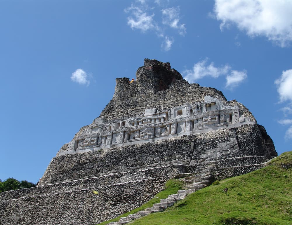 A towering ancient structure with stone steps and carvings against a blue sky.