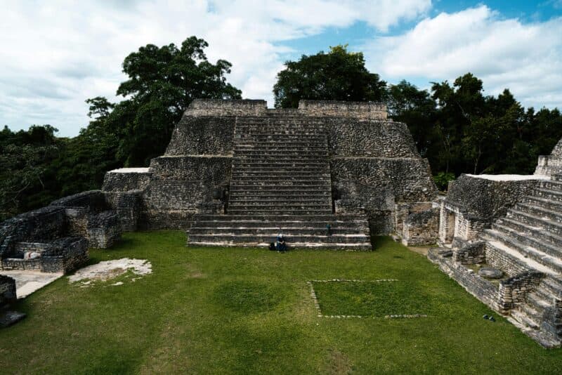 Ancient stone steps rise towards a partially clouded sky, surrounded by lush greenery.