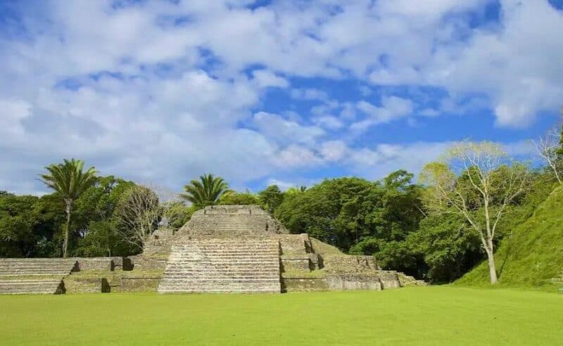 Ancient stone steps rise from a lush green landscape under a partly cloudy sky.