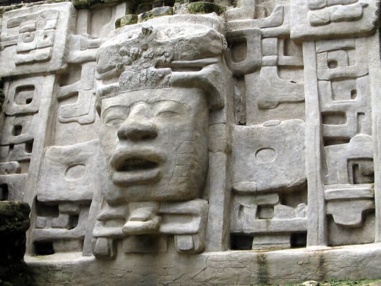 Carved stone relief depicting a human face surrounded by intricate geometric designs.