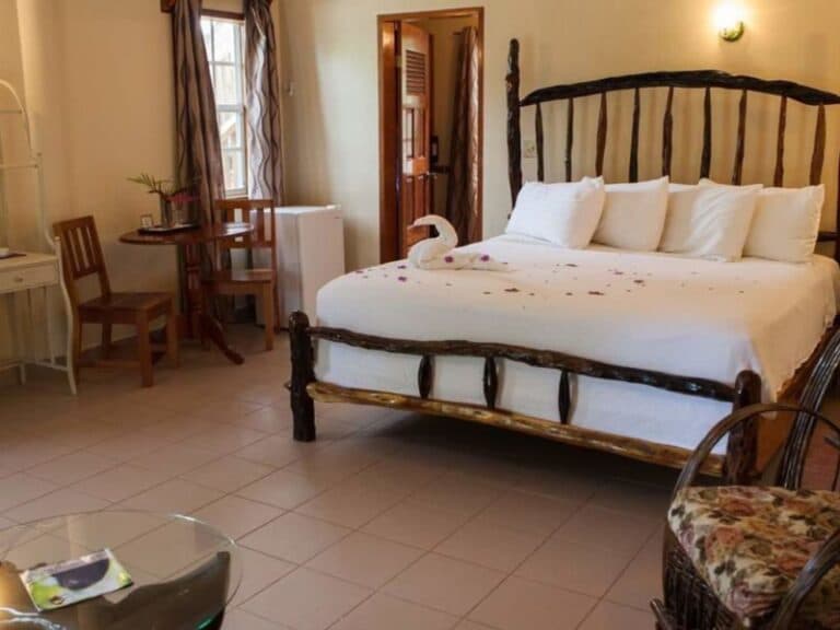 Cozy hotel room featuring a rustic wooden bed, a small dining table, and decorative elements.