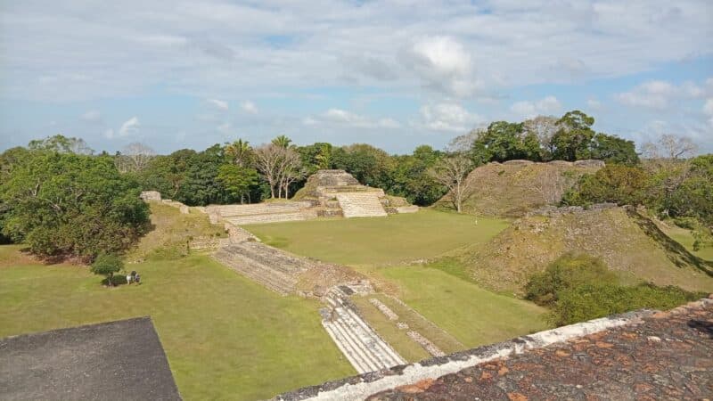 Ancient ruins surrounded by lush greenery under a partly cloudy sky.