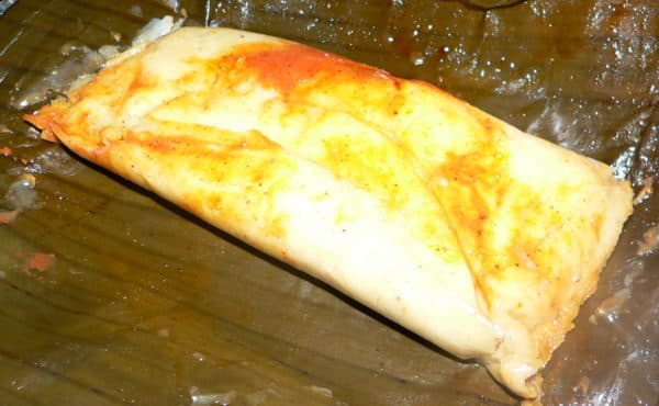A tamale wrapped in a banana leaf.