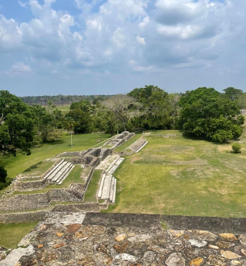 View of ancient ruins surrounded by lush greenery under a partly cloudy sky.