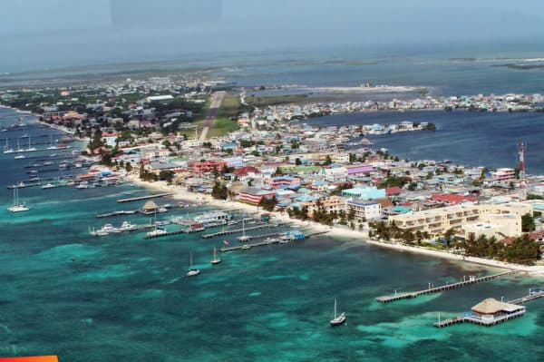 Aerial view of a colorful coastal town with boats docked and turquoise waters.