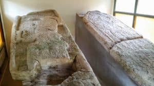 Two ancient stone sarcophagi displayed indoors.