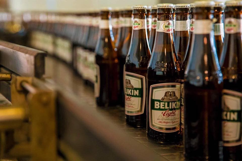 A row of glass bottles of Belikin beer on a production line.