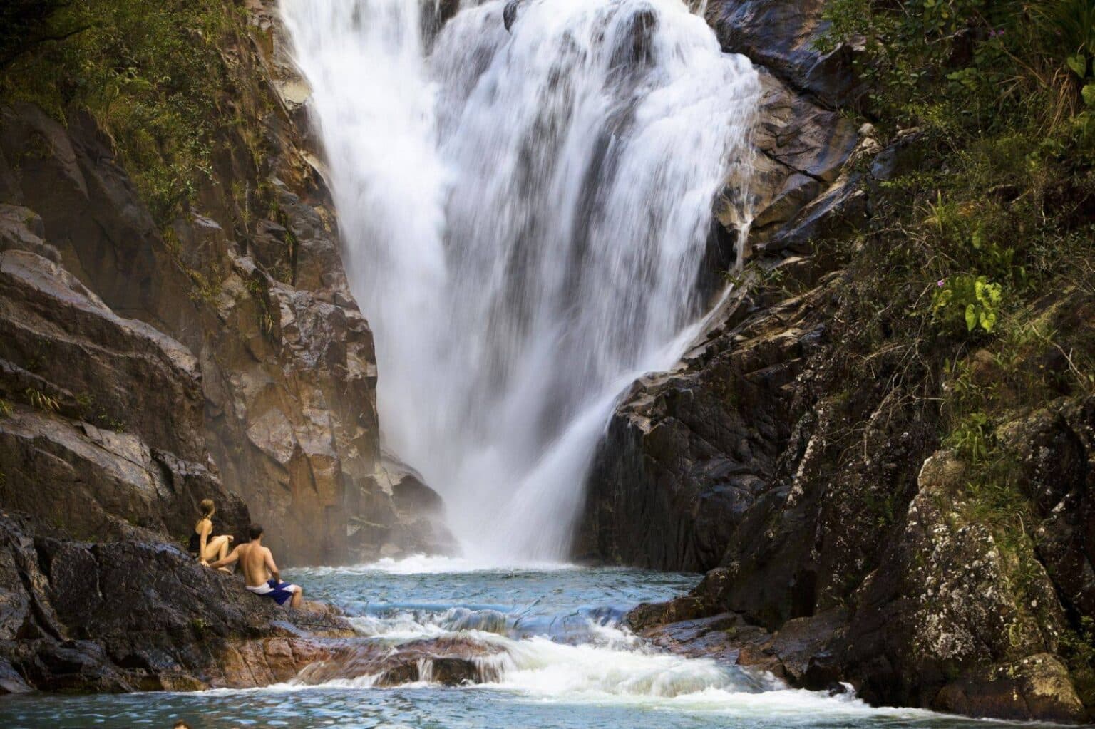 A person relaxes by a stunning waterfall in a serene natural setting.