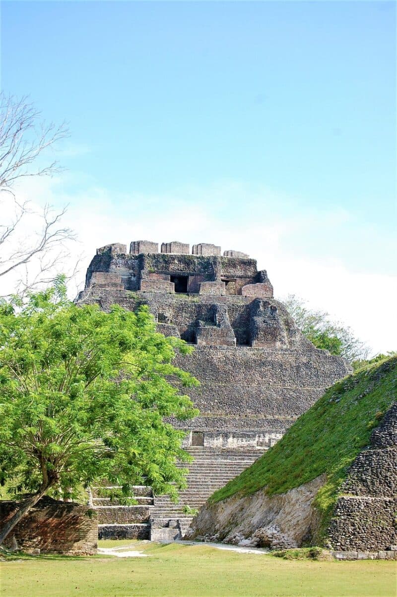 Ancient stone pyramid surrounded by lush greenery under a blue sky.