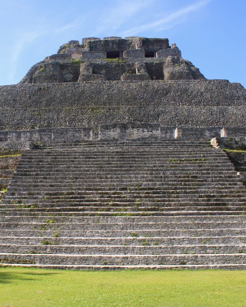 A large stone pyramid structure with visible steps and weathered walls under a blue sky.