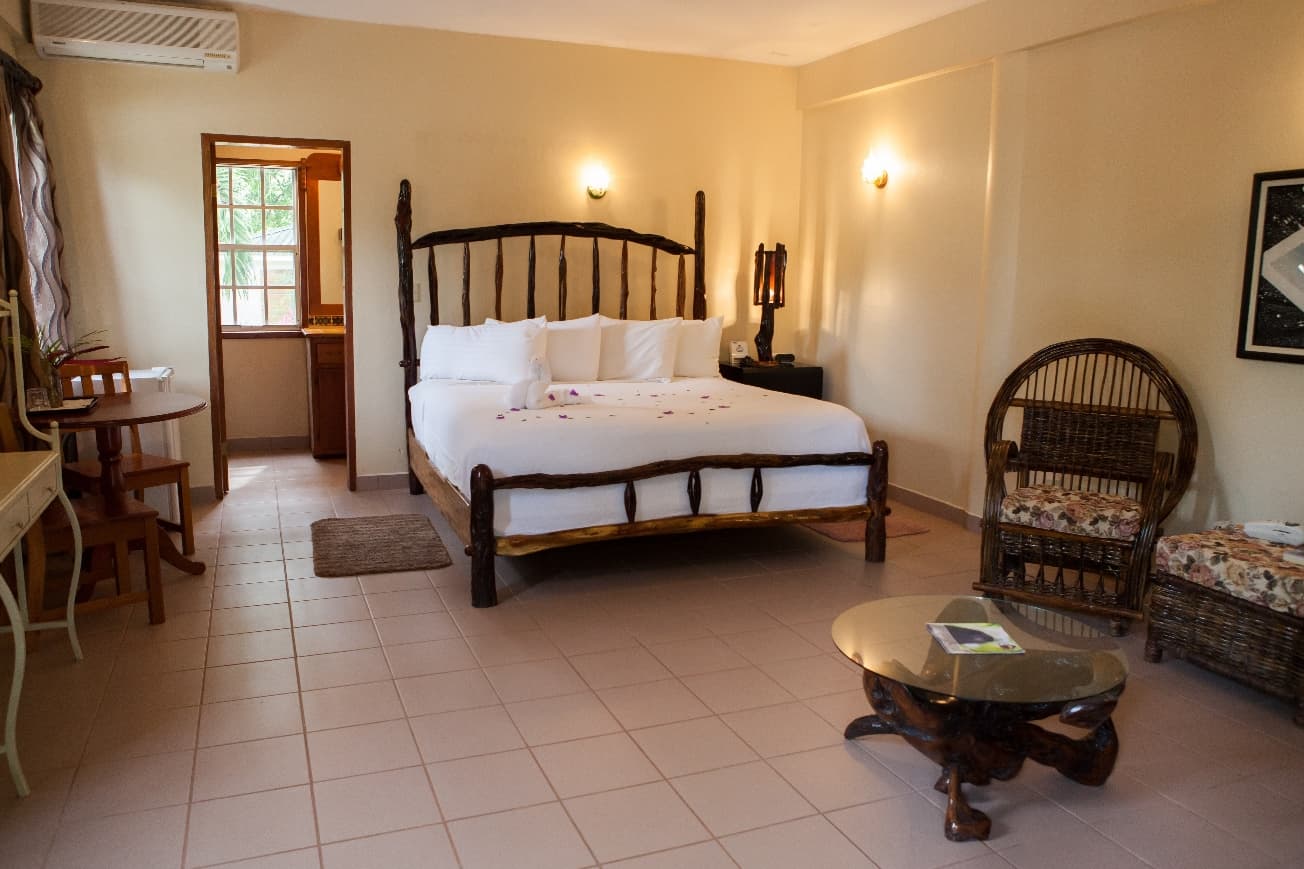 A cozy hotel room featuring a wooden bed, seating area, and natural light from a window.