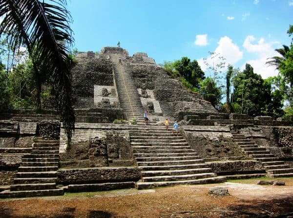 Ancient stone pyramid with steps surrounded by jungle.