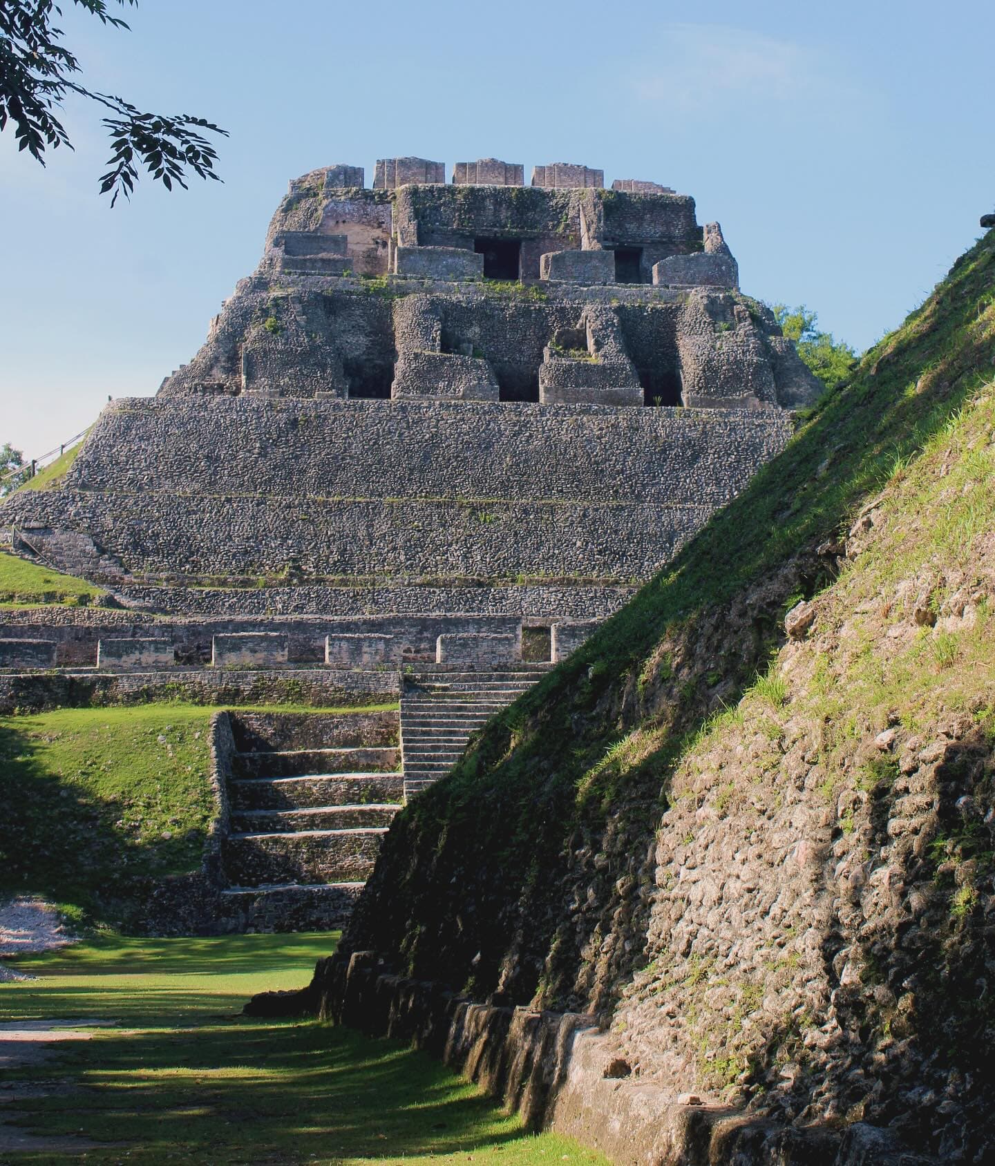 A stone pyramid structure with steps, surrounded by greenery and trees.