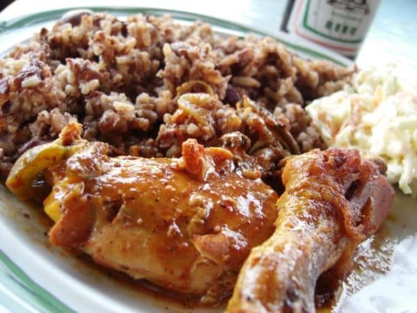 A plate featuring seasoned chicken, rice and beans, and coleslaw.