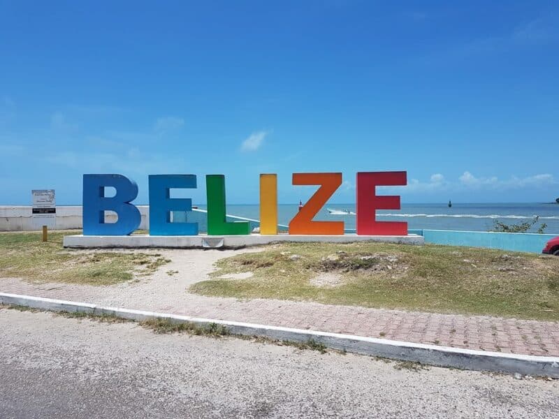 Colorful "BELIZE" sign beside the ocean under a blue sky.