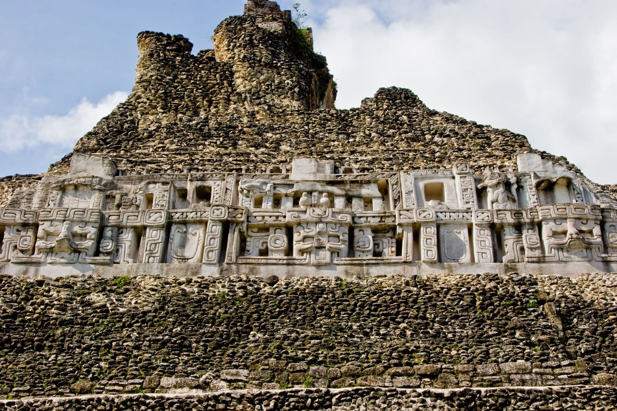 Ancient stone structure with intricate carvings against a cloudy sky.
