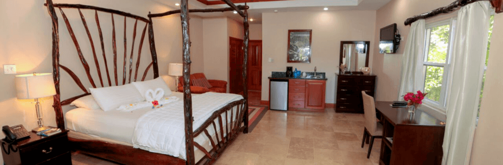 A stylish bedroom featuring a wooden four-poster bed, modern amenities, and warm lighting.
