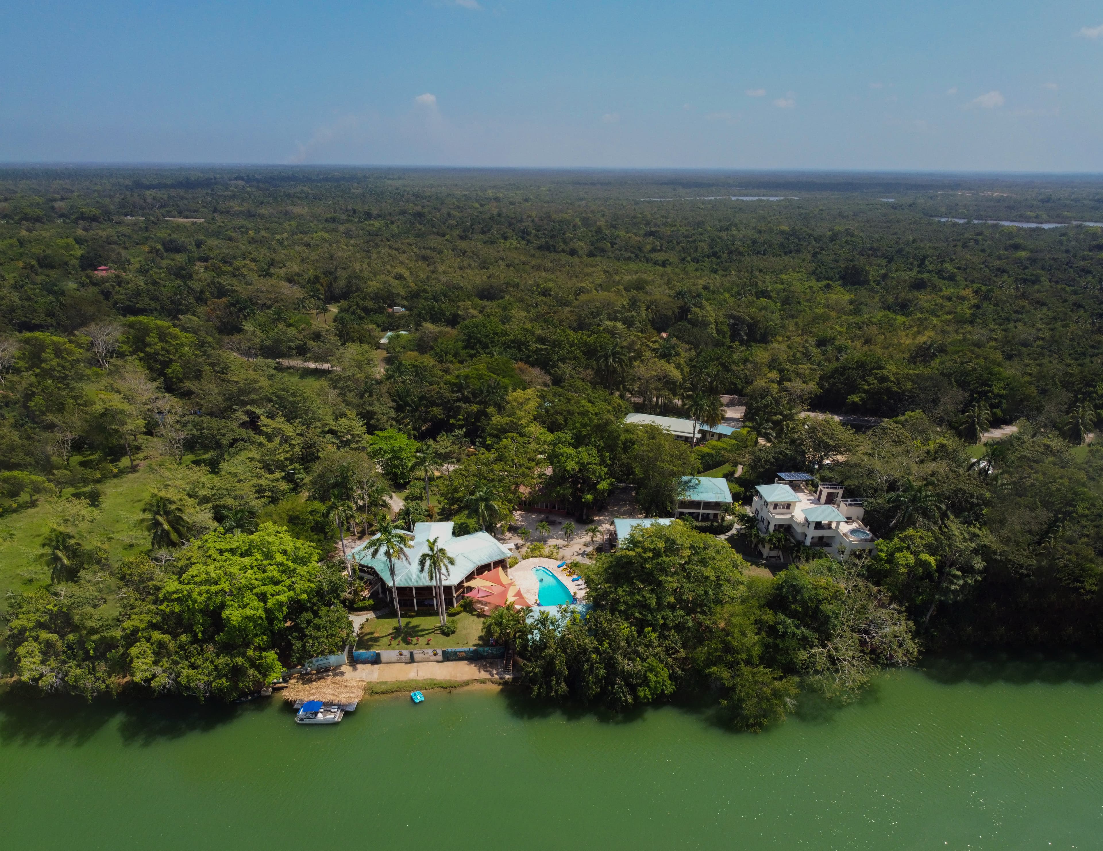 Aerial view of a lush landscape featuring a resort with a pool alongside a river.