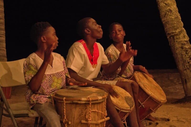 Three young drummers playing traditional drums under the night sky.