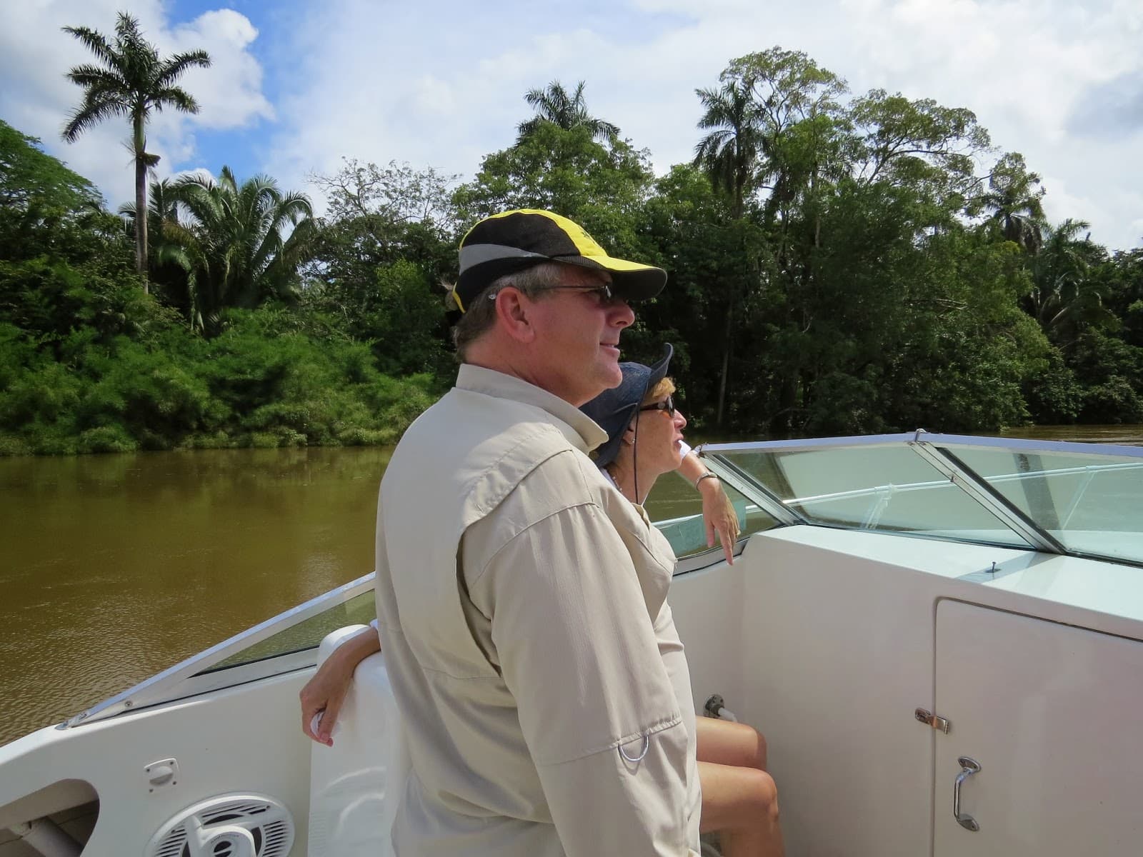 A man and woman enjoy a scenic boat ride along a lush, green river.