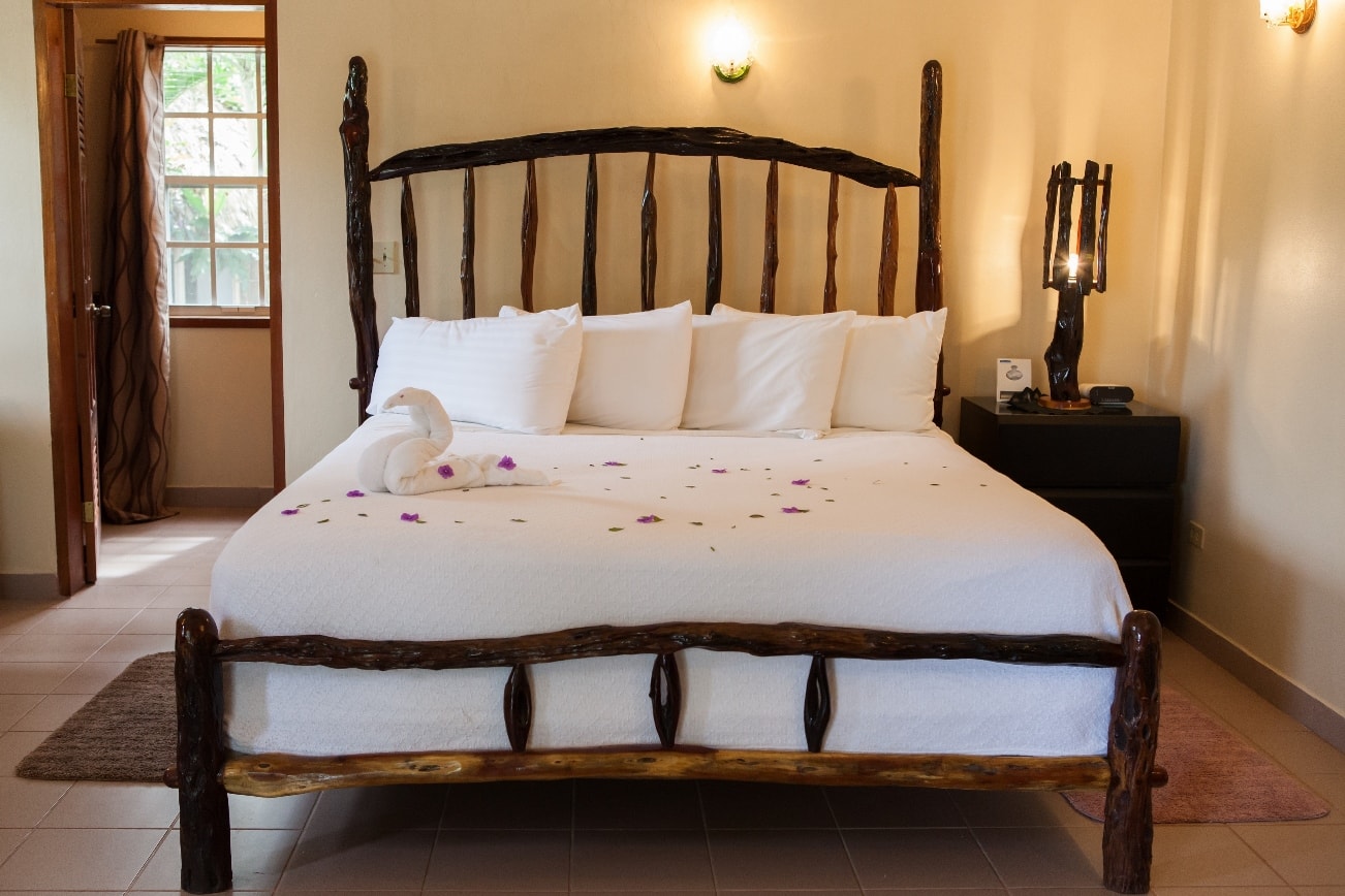 A cozy bedroom featuring a rustic wooden bed adorned with white linens and pink flower petals.