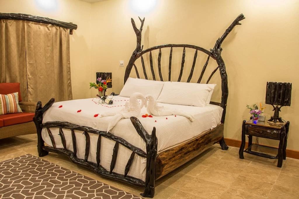 A beautifully arranged bedroom featuring a rustic wood bed, decorative floral accents, and a cozy seating area.