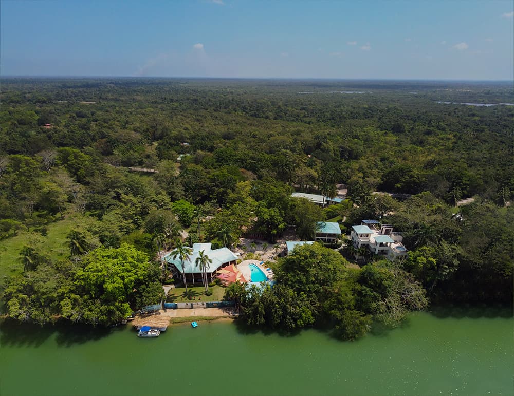 Aerial view of a lush green landscape with a river and a resort featuring a pool.
