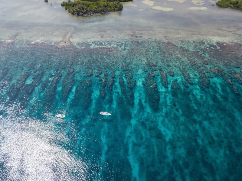 Aerial view of clear turquoise waters and coral reefs with two boats.