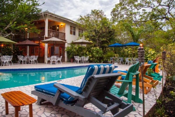 A tranquil pool area surrounded by colorful lounge chairs and a lush garden.