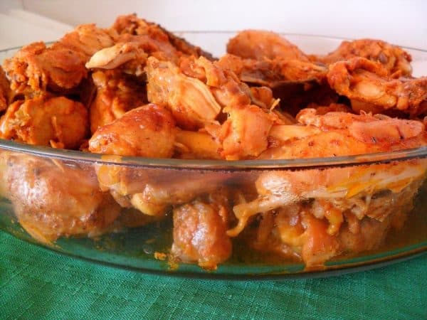A glass dish filled with seasoned, cooked chicken pieces.