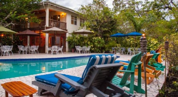 A tranquil pool area featuring colorful lounge chairs and surrounded by lush greenery and patio furniture.