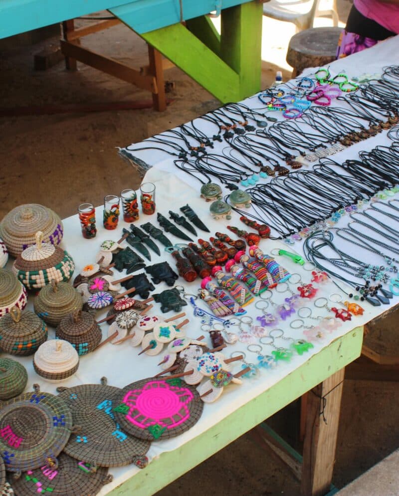 A variety of handmade crafts and jewelry displayed on a white tablecloth.