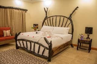 A rustic bedroom featuring a wooden bed with decorative swans and rose petals, along with a cozy seating area.