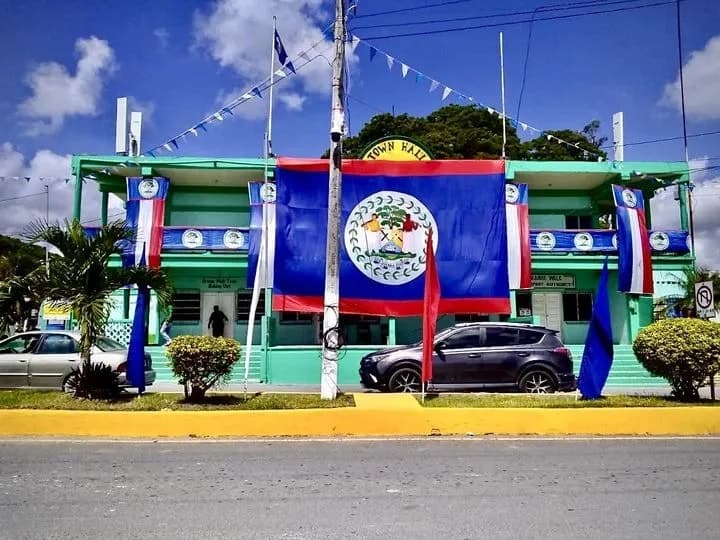 A vibrant town hall building decorated with the Belizean flag and colorful banners.
