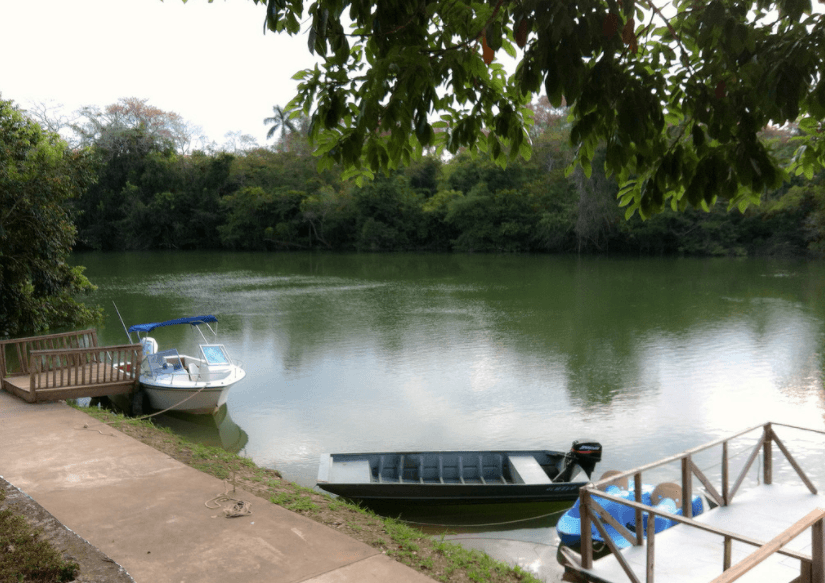 A tranquil riverside scene with two boats moored near a lush, green shoreline.