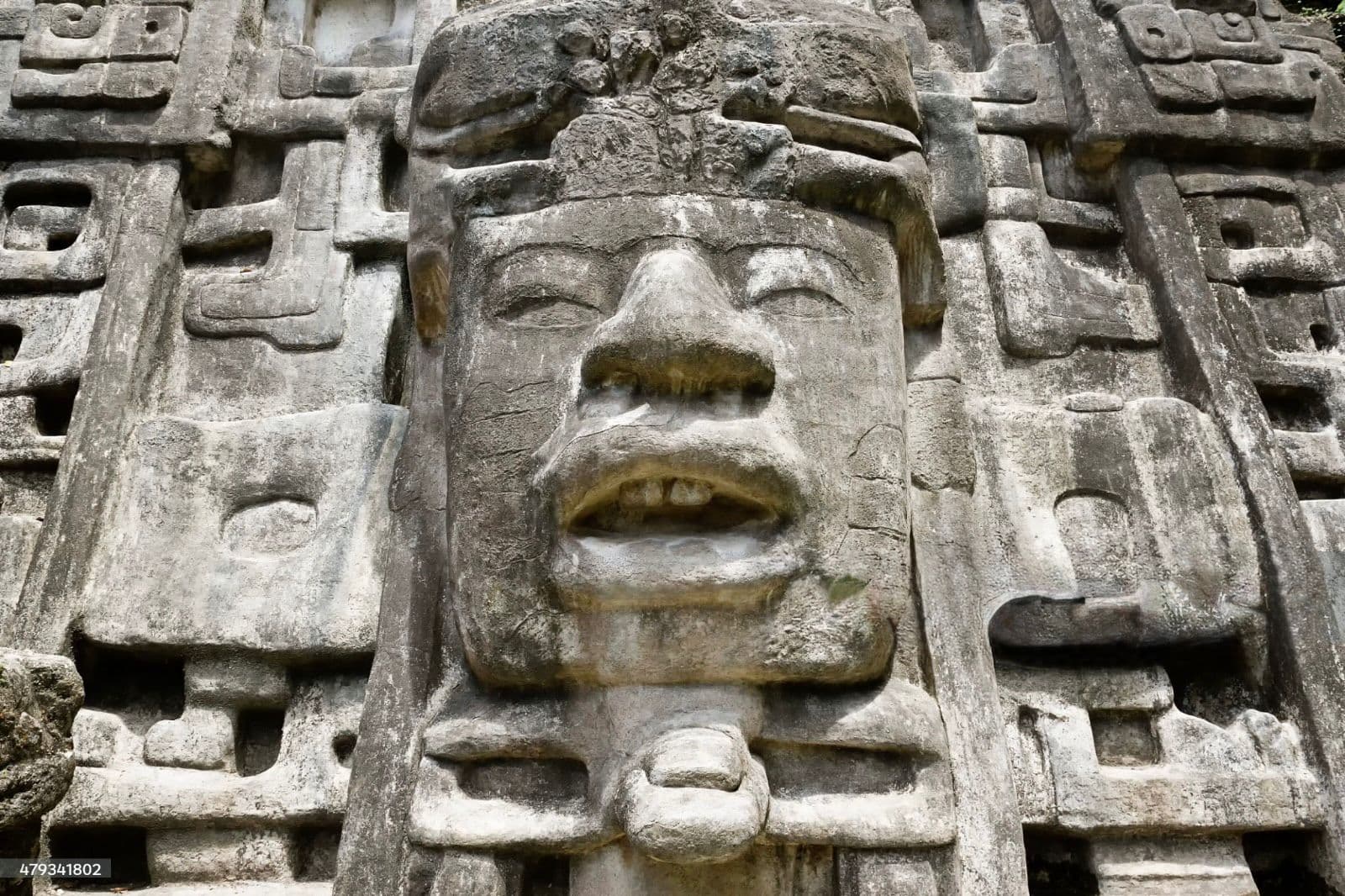 A close-up of an ancient stone sculpture depicting a face with intricate carvings.