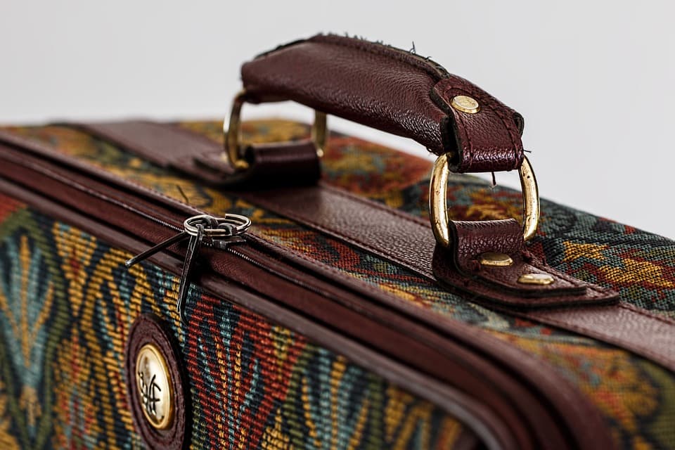 Close-up of a patterned suitcase handle with leather accents.