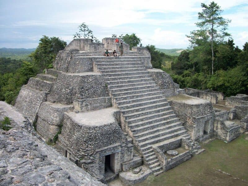 Ancient stone pyramid with stairs surrounded by lush greenery.